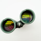 A pair of green binoculars displayed upright on a white branded stand against a clean white background.