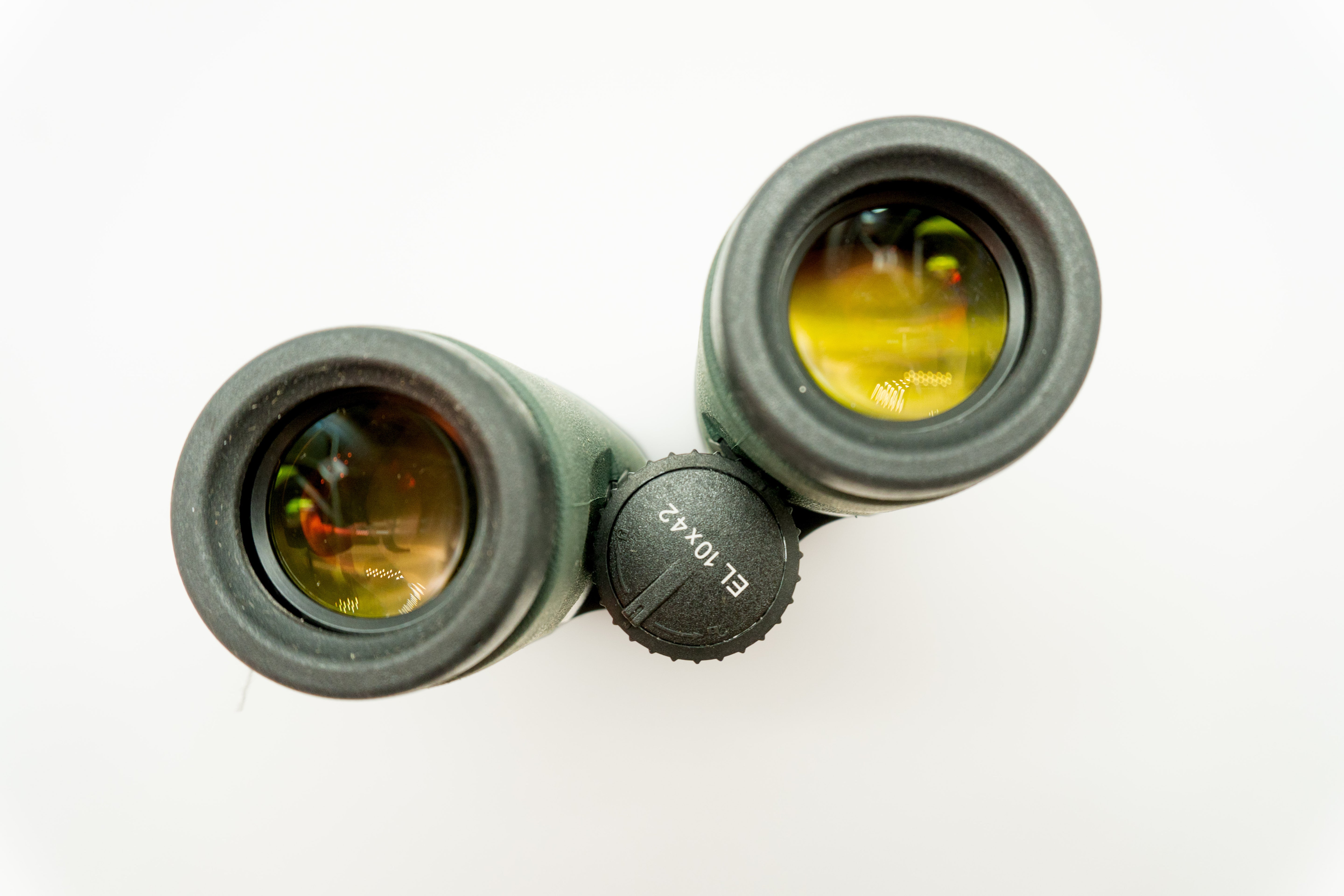 A pair of green binoculars displayed upright on a white branded stand against a clean white background.