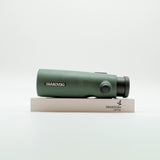 A pair of green binoculars displayed upright on a white branded stand against a clean white background.
