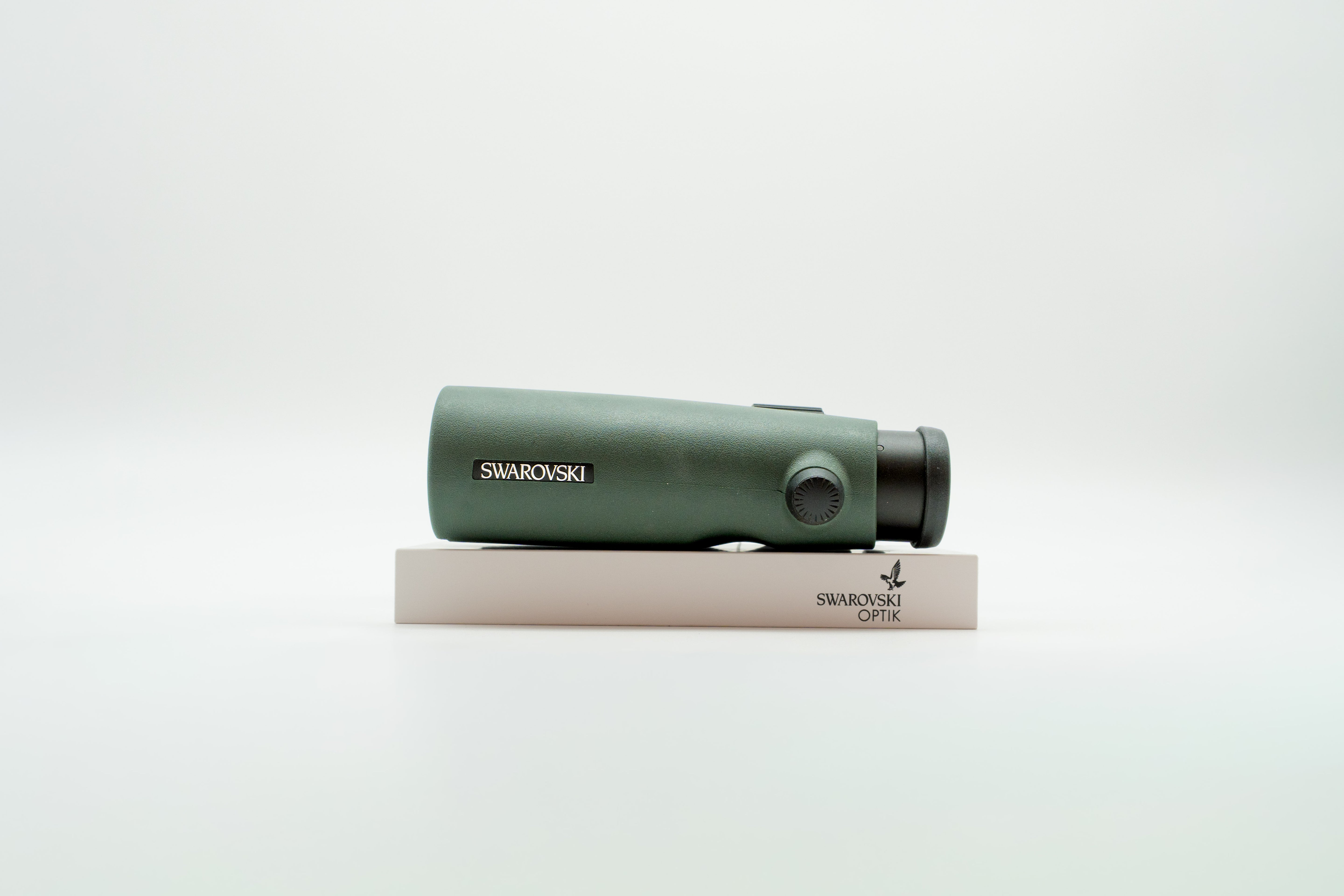 A pair of green binoculars displayed upright on a white branded stand against a clean white background.
