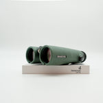 A pair of green binoculars displayed upright on a white branded stand against a clean white background.