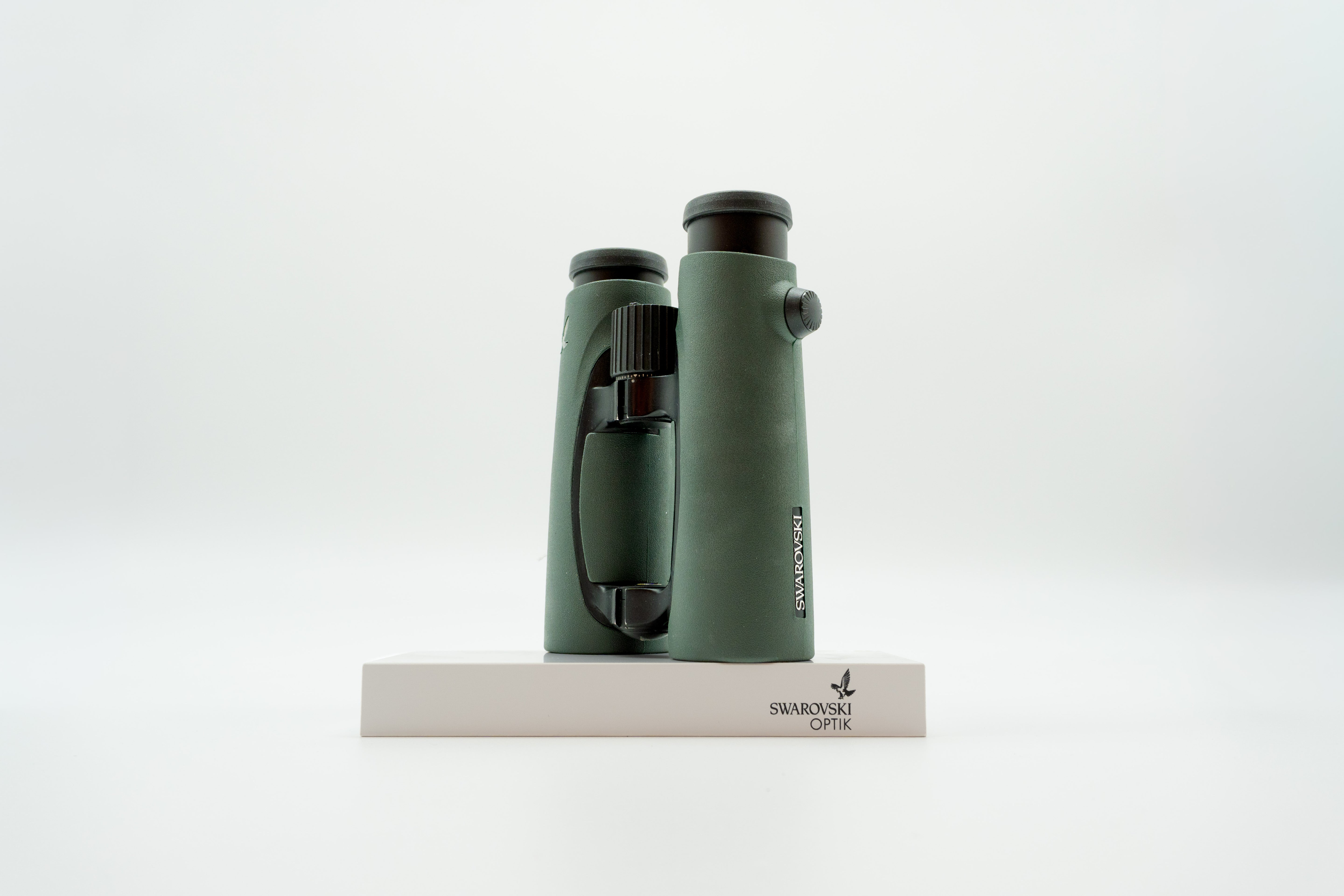 A pair of green binoculars displayed upright on a white branded stand against a clean white background.