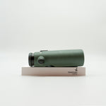 A pair of green binoculars displayed upright on a white branded stand against a clean white background.
