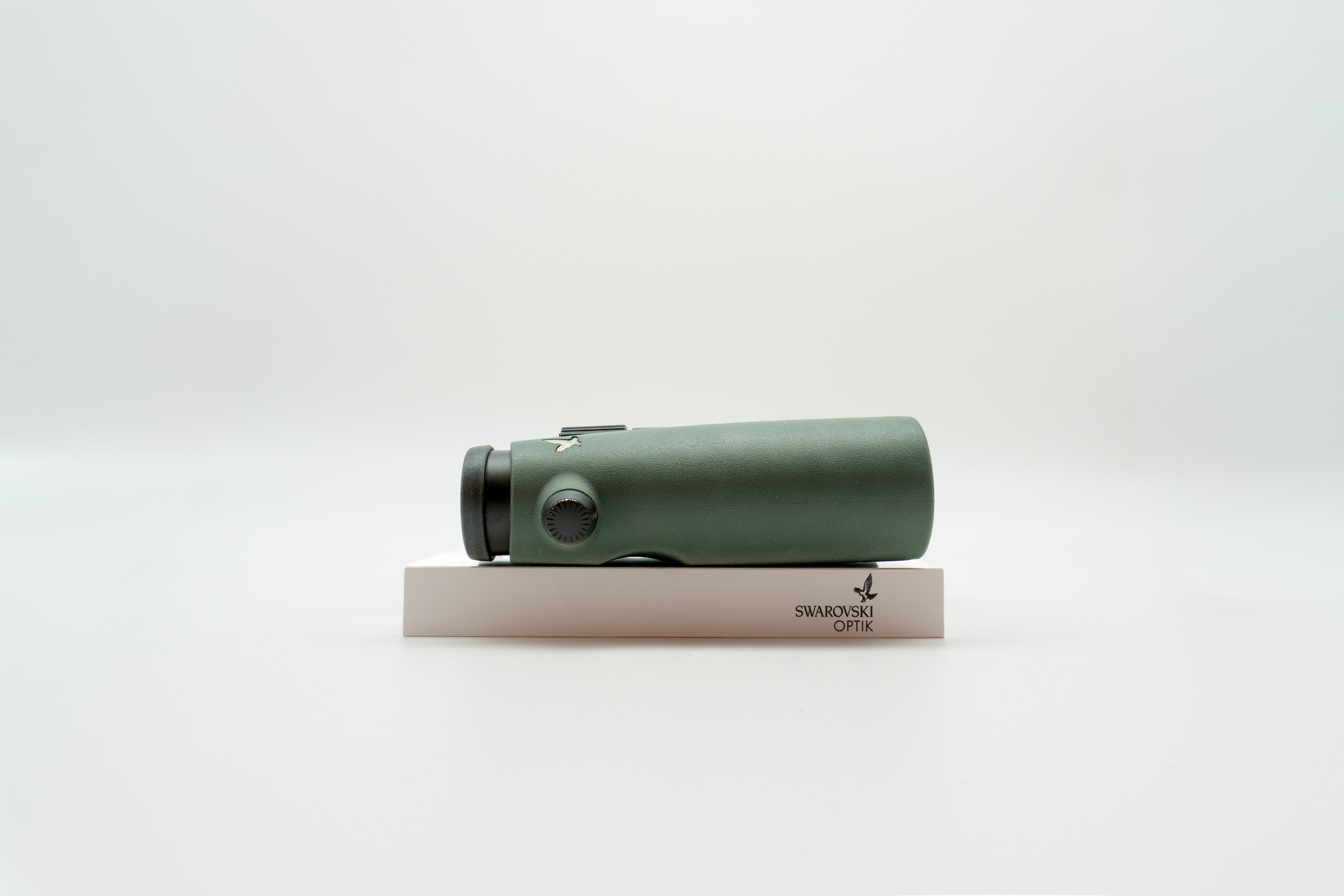 A pair of green binoculars displayed upright on a white branded stand against a clean white background.