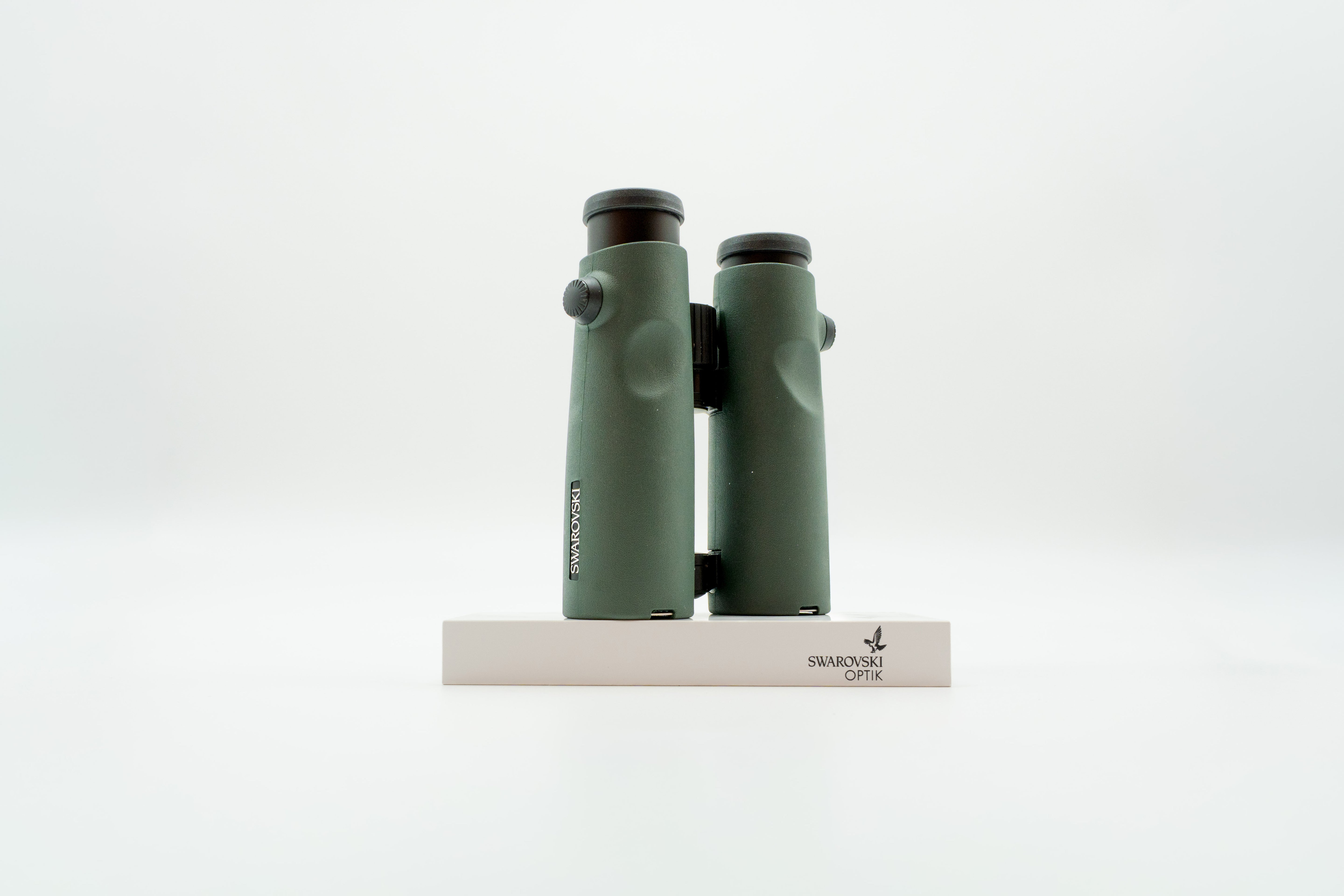 A pair of green binoculars displayed upright on a white branded stand against a clean white background.