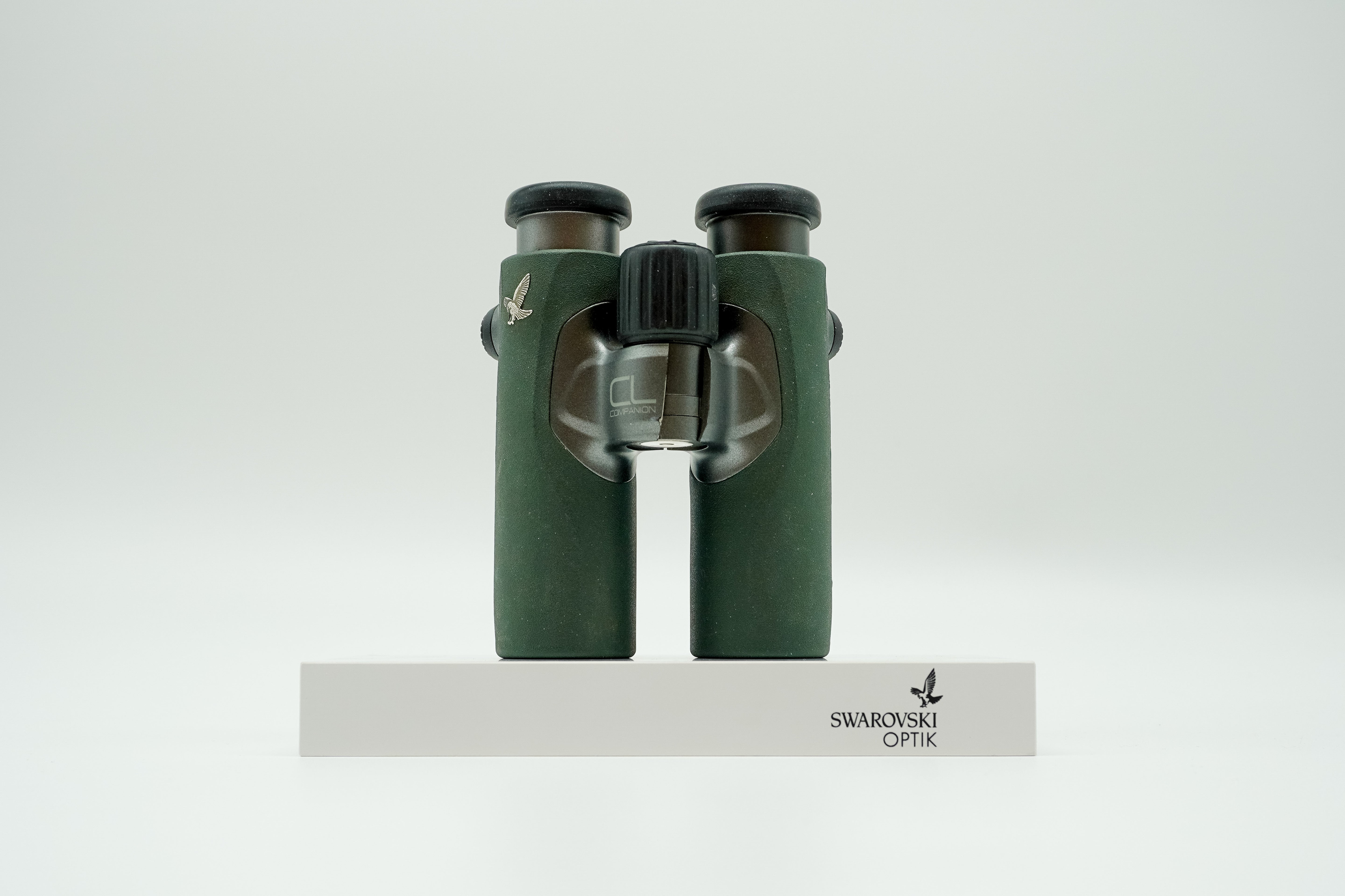 SWAROVSKI green cl pocket binoculars with white background on a stand.