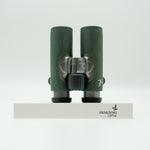 SWAROVSKI green cl pocket binoculars with white background on a stand.