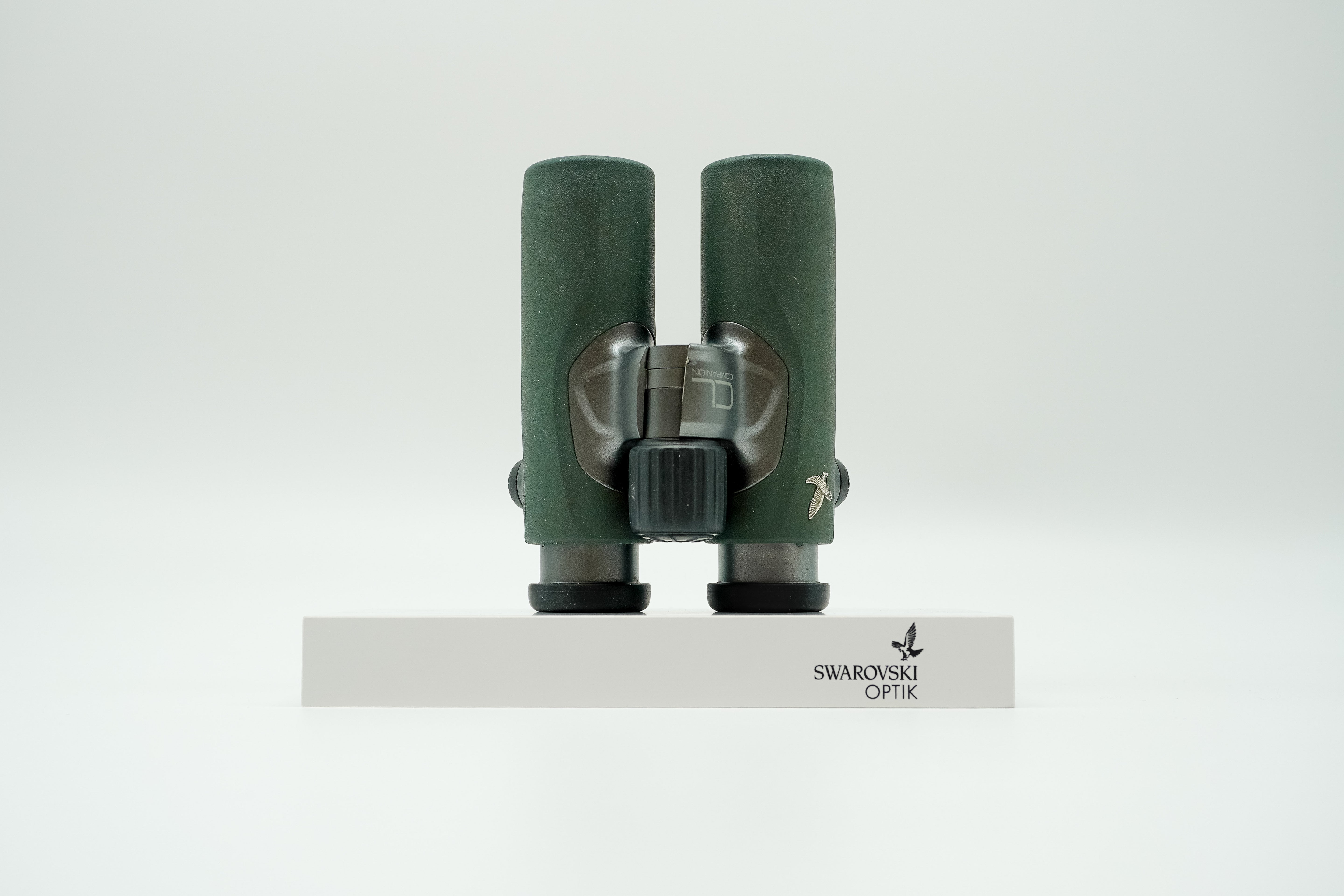 SWAROVSKI green cl pocket binoculars with white background on a stand.