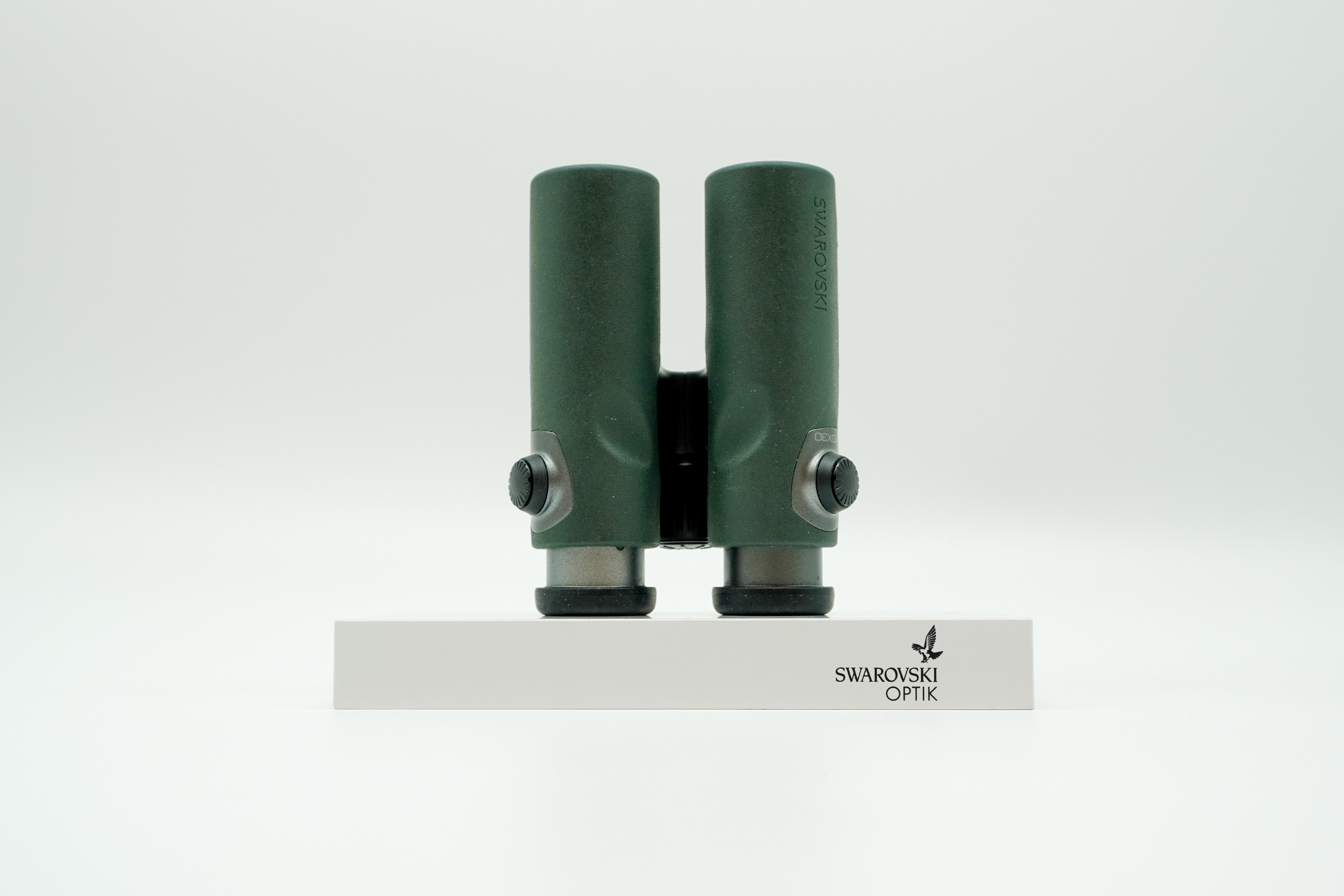 SWAROVSKI green cl pocket binoculars with white background on a stand.