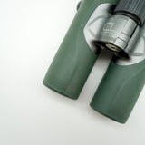 SWAROVSKI green cl pocket binoculars with white background on a stand.
