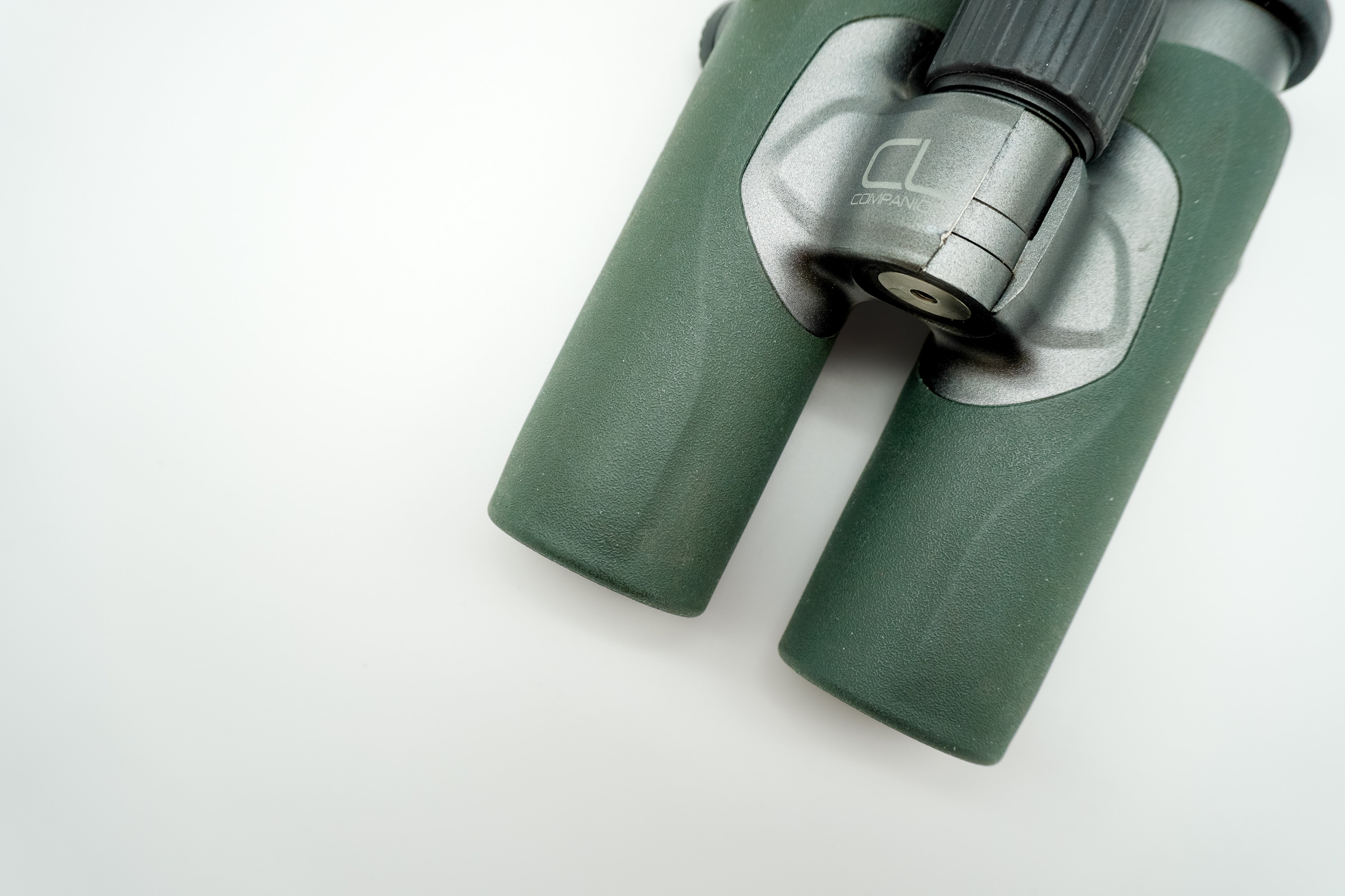 SWAROVSKI green cl pocket binoculars with white background on a stand.