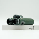 SWAROVSKI green cl pocket binoculars with white background on a stand.