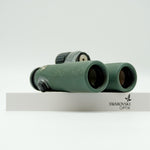 SWAROVSKI green cl pocket binoculars with white background on a stand.