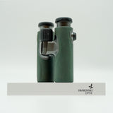 SWAROVSKI green cl pocket binoculars with white background on a stand.