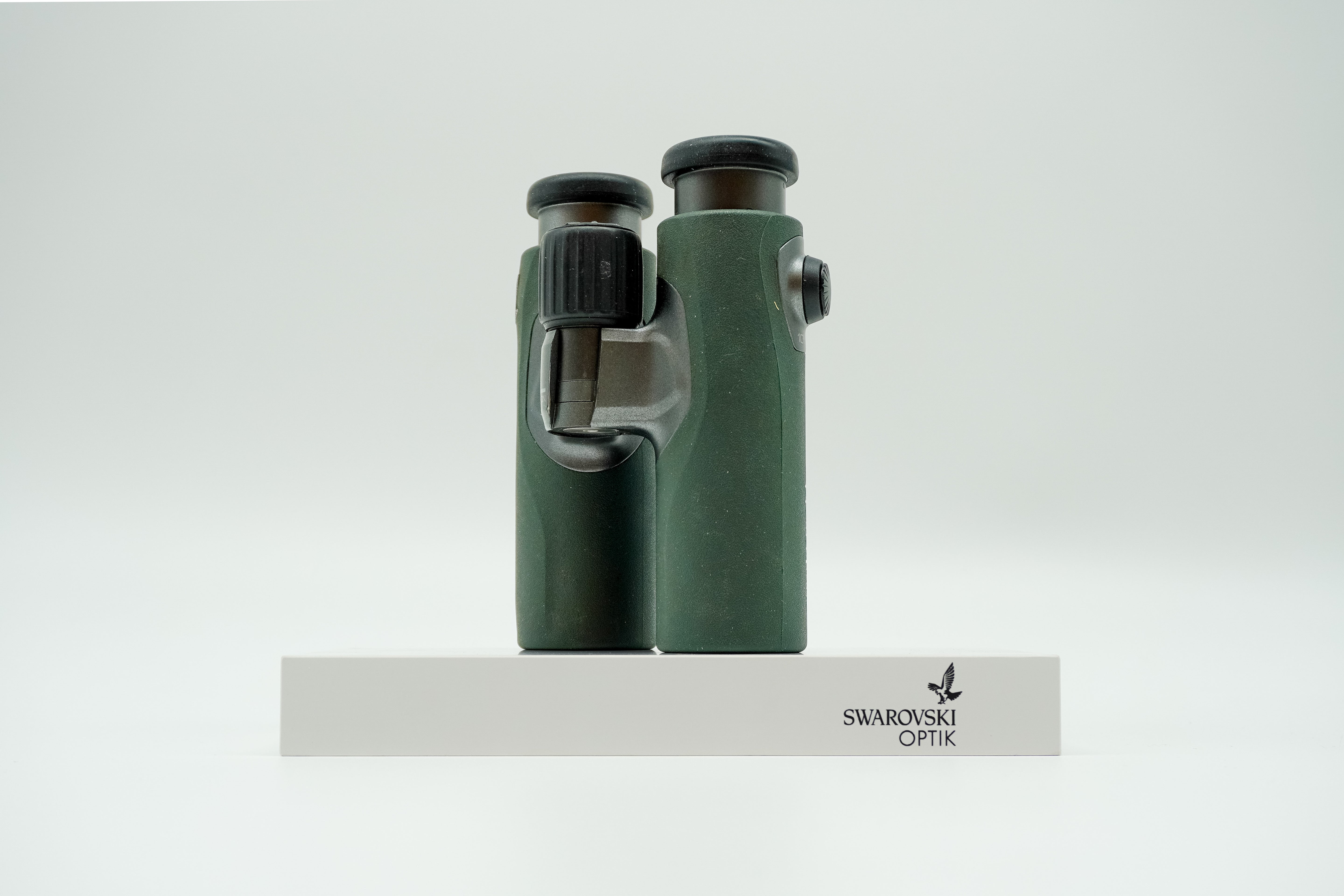 SWAROVSKI green cl pocket binoculars with white background on a stand.