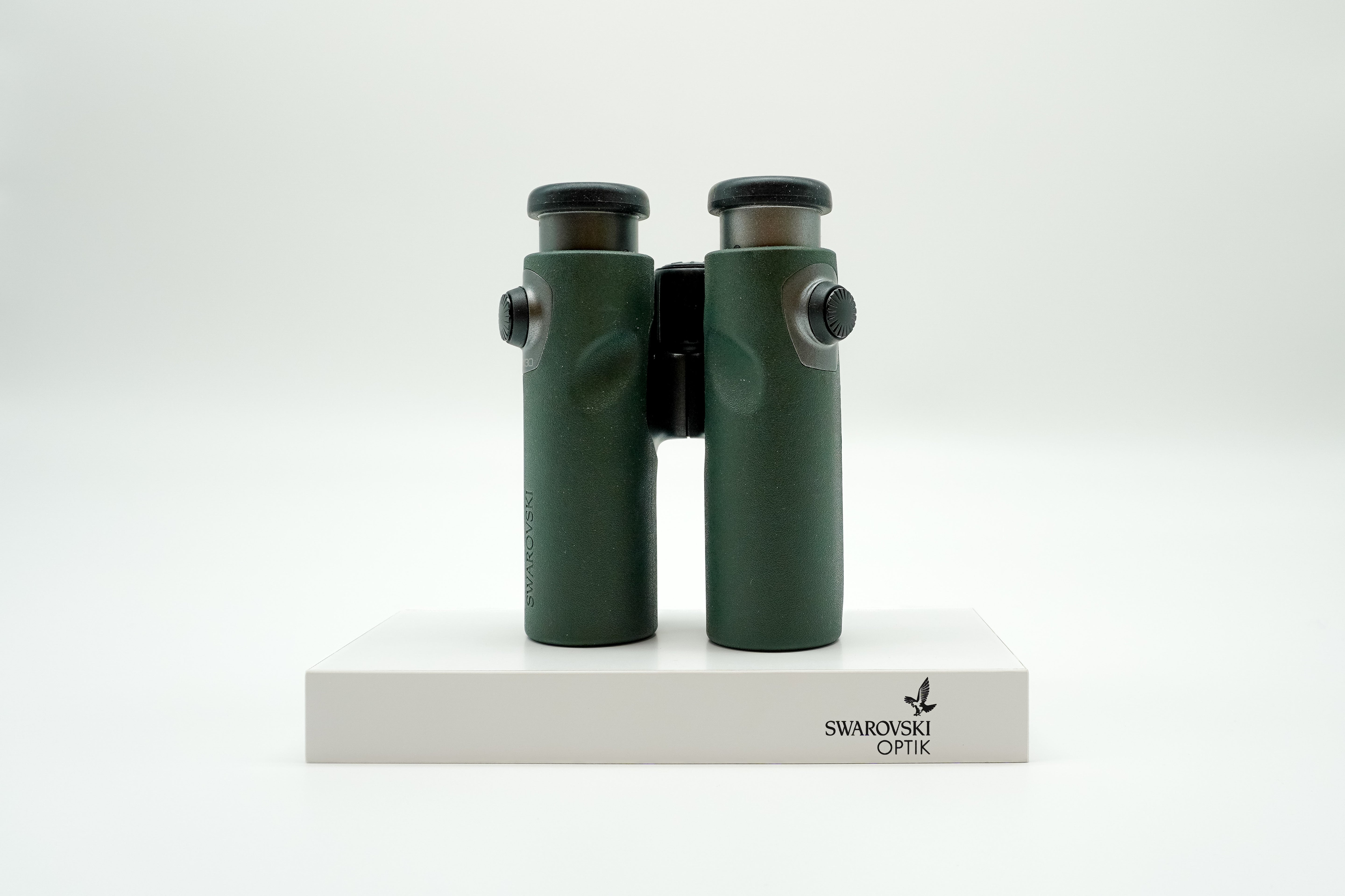 SWAROVSKI green cl pocket binoculars with white background on a stand.