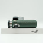 SWAROVSKI green cl pocket binoculars with white background on a stand.