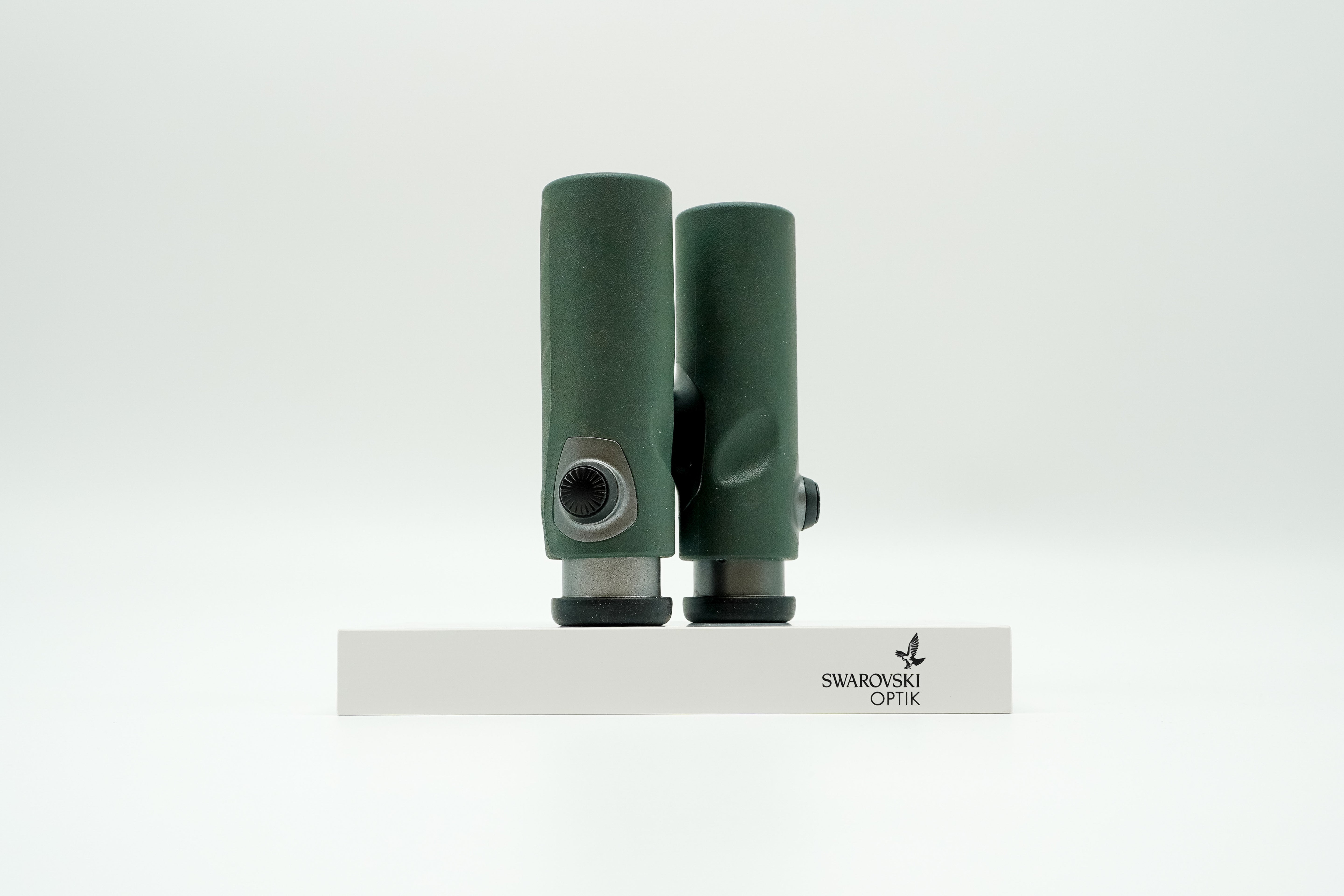 SWAROVSKI green cl pocket binoculars with white background on a stand.