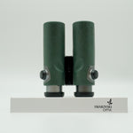 SWAROVSKI green cl pocket binoculars with white background on a stand.