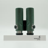 SWAROVSKI green cl pocket binoculars with white background on a stand.