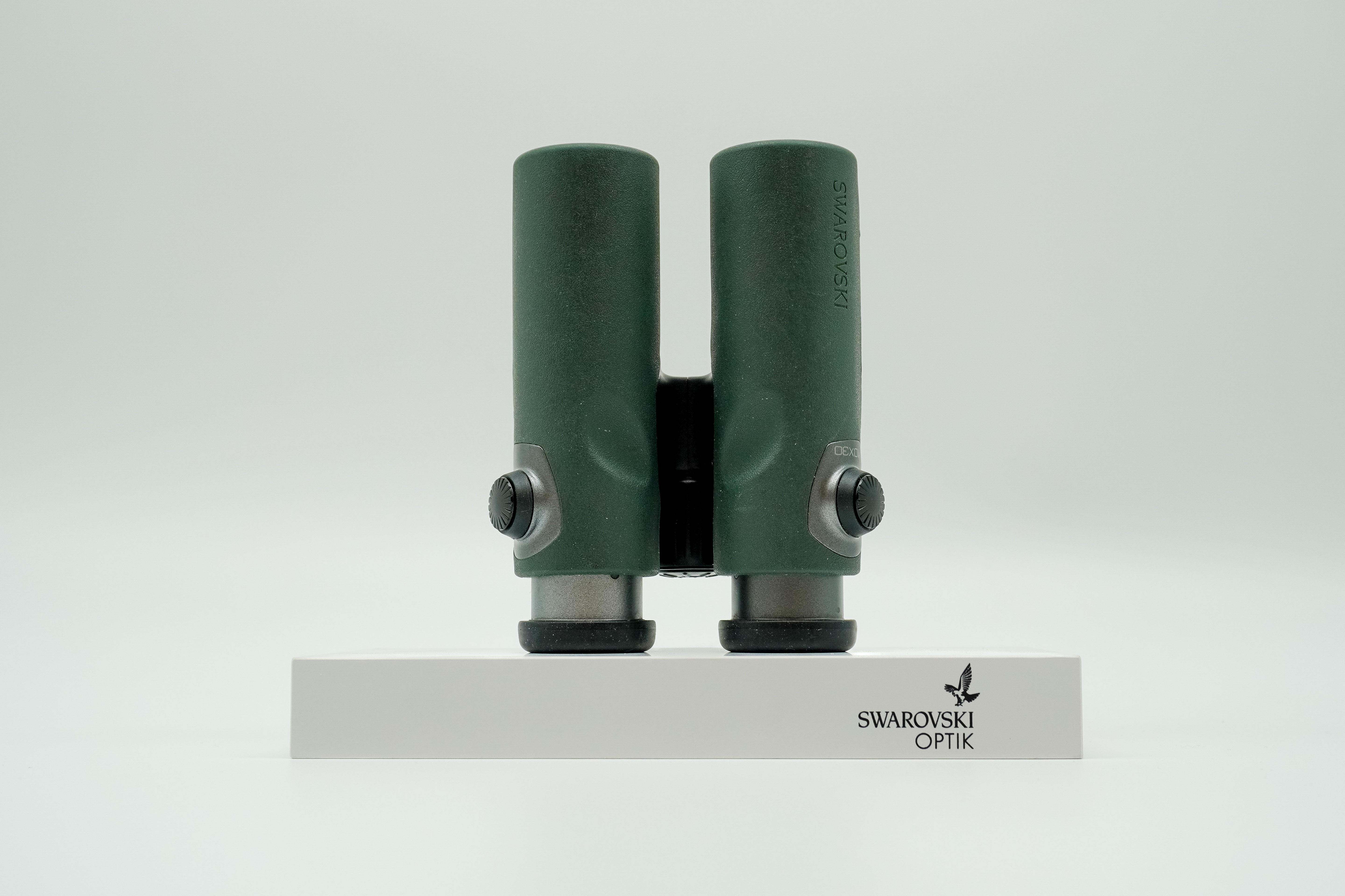 SWAROVSKI green cl pocket binoculars with white background on a stand.