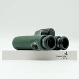 SWAROVSKI green cl pocket binoculars with white background on a stand.