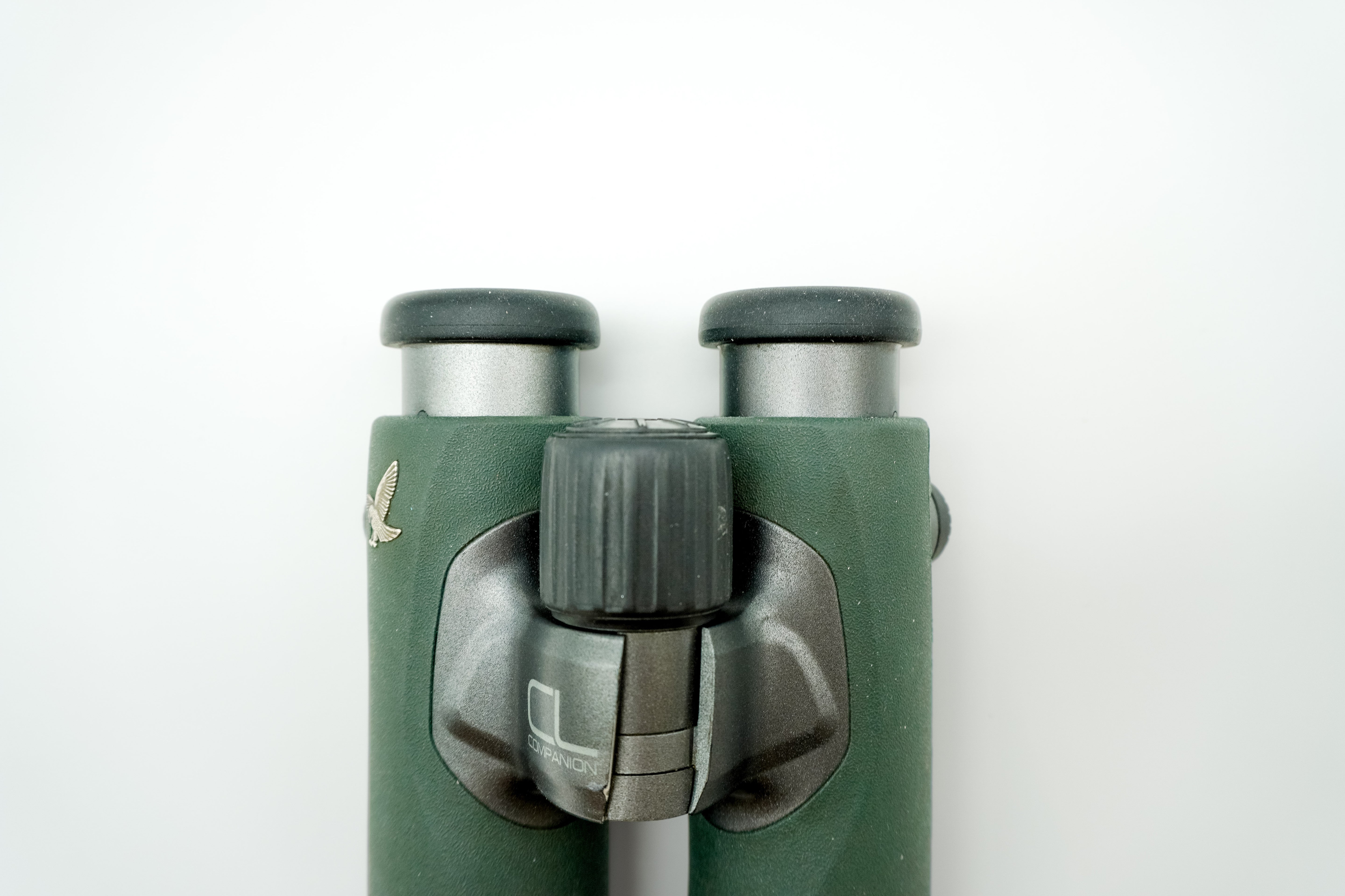 SWAROVSKI green cl pocket binoculars with white background on a stand.