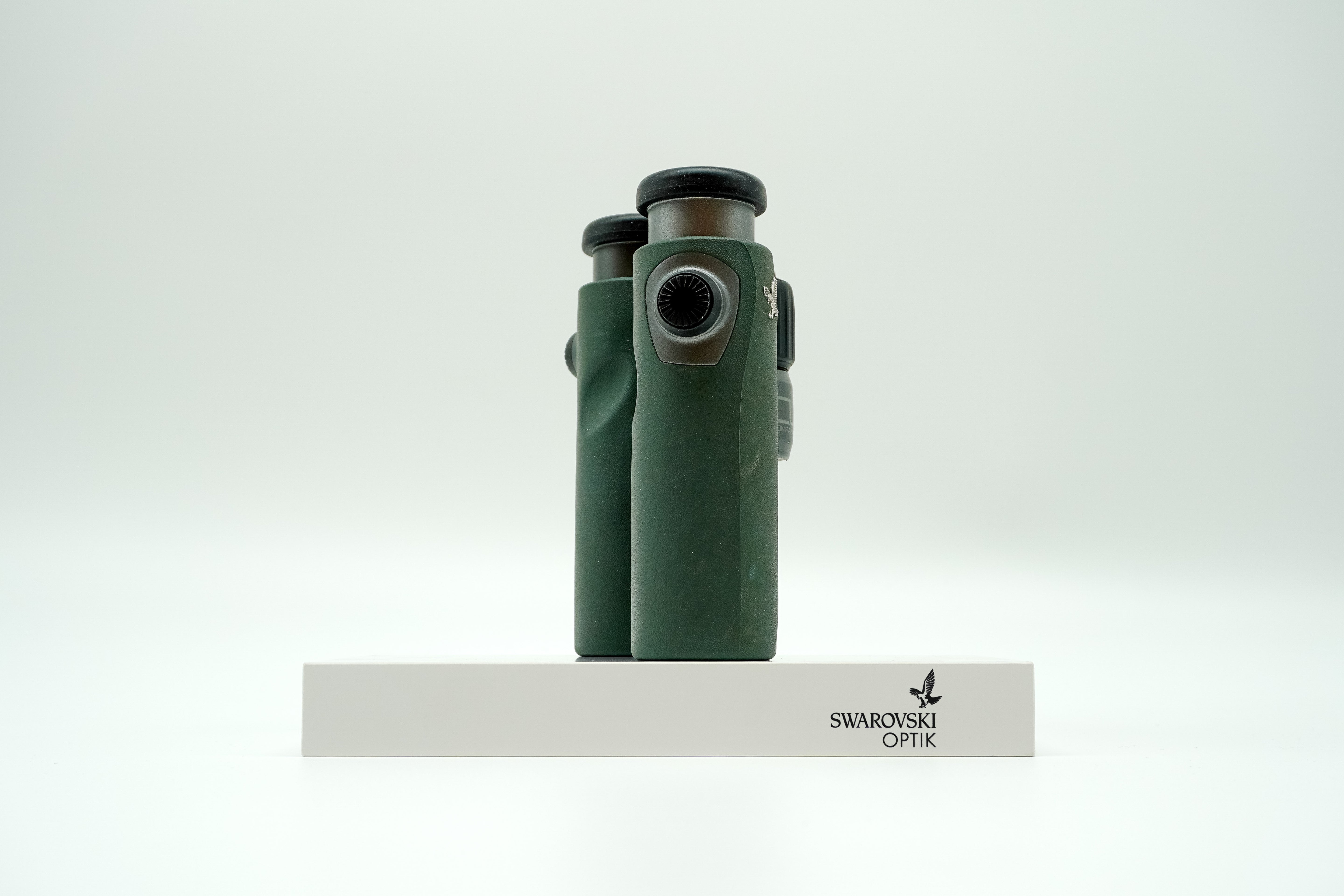 SWAROVSKI green cl pocket binoculars with white background on a stand.